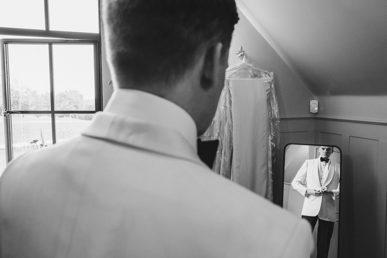 Black and white photo showing wedding preparations in a room with natural window light.