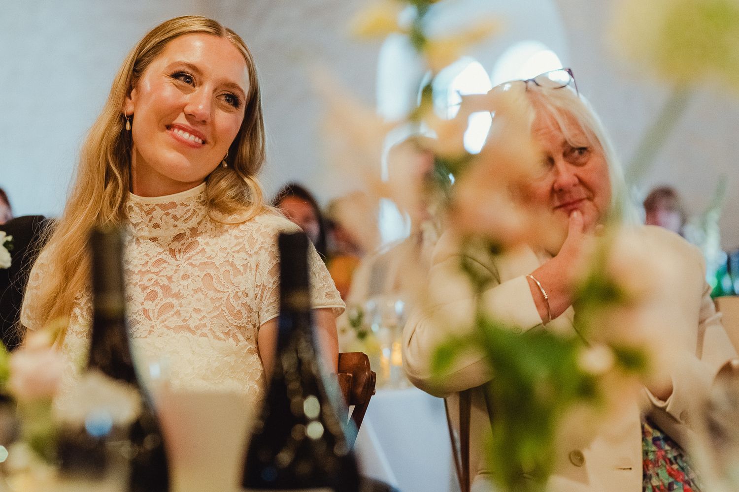 Elegant wedding scene with celebratory smiles and laughter in a sun-lit room with white floral accents.