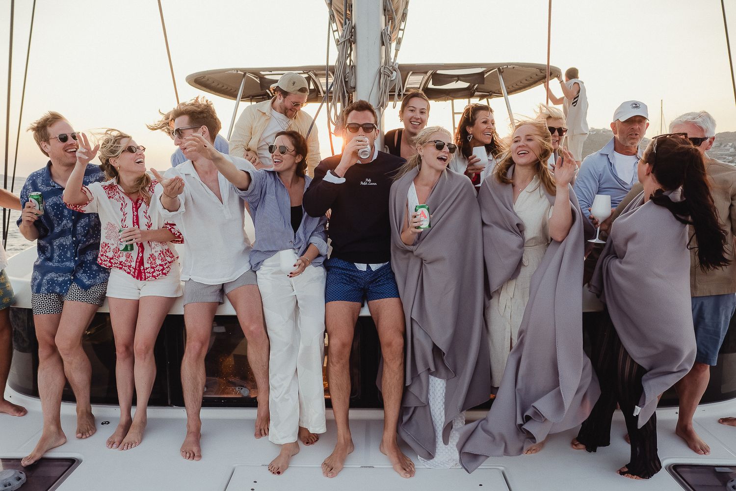 A group of party-goers enjoying drinks and celebrations together on a boat deck during a sunny day.