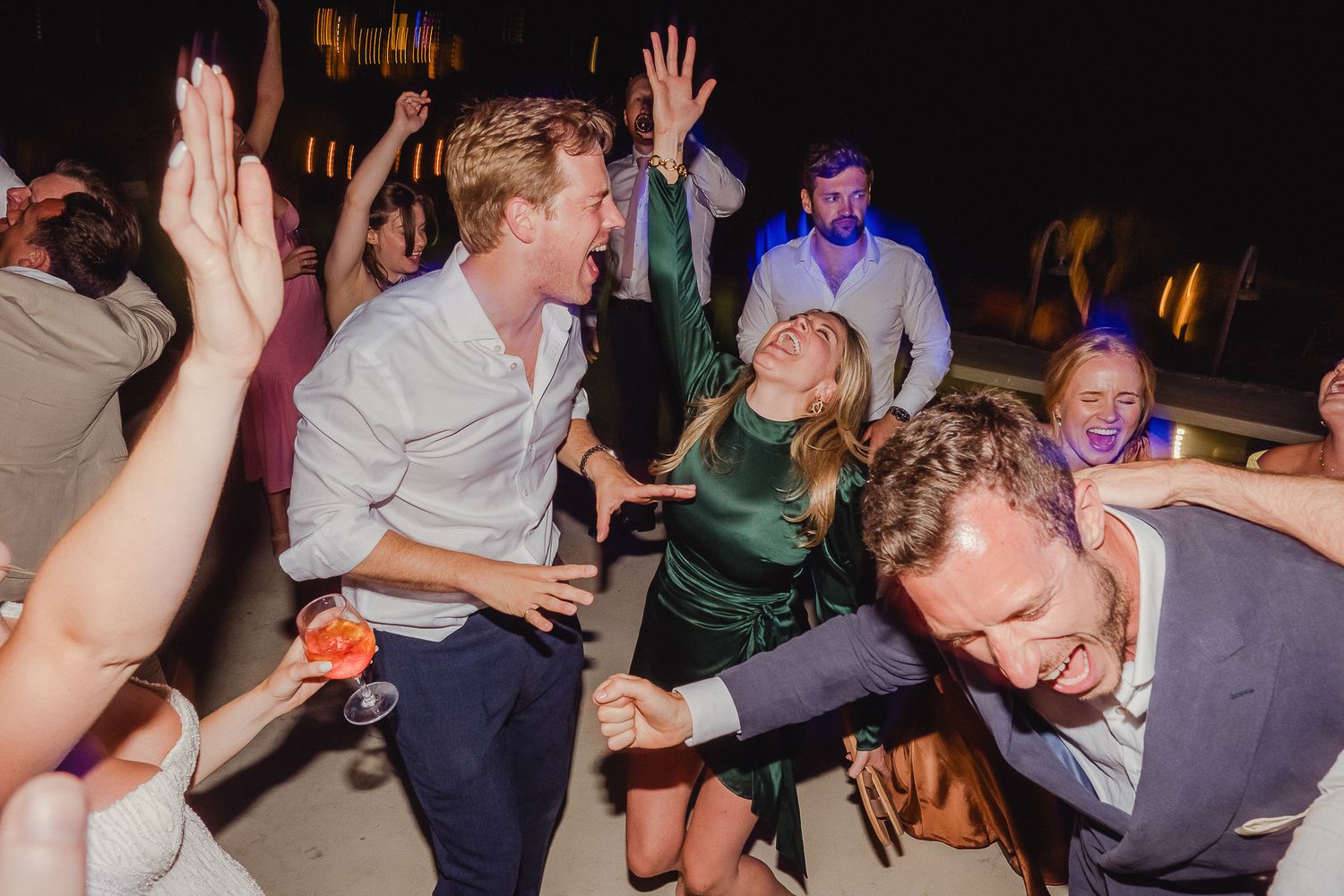 Dancers move energetically on a dark dance floor during what appears to be a lively party or celebration event.
