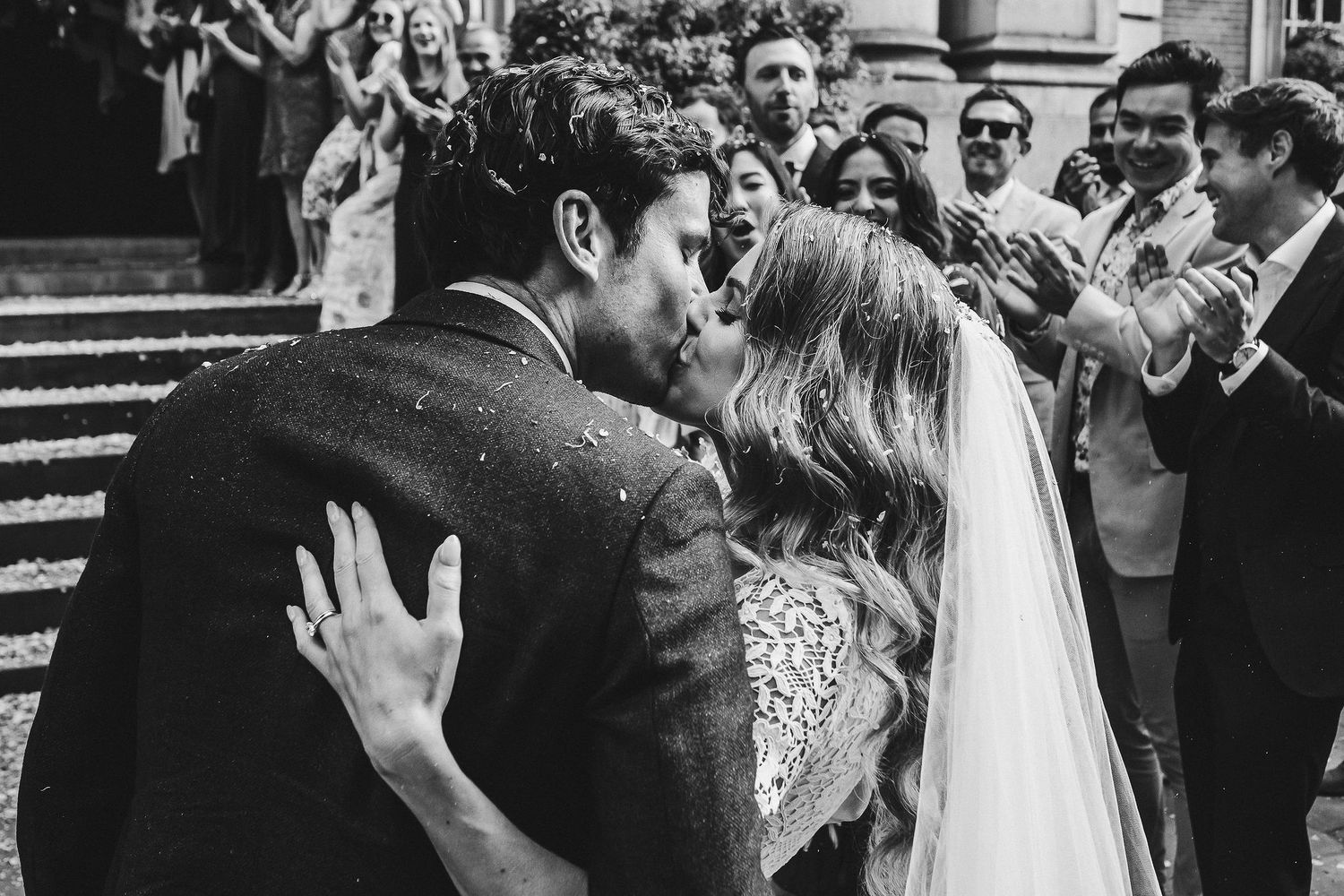 A black and white photo showing a crowd dancing and celebrating at what appears to be a wedding reception.