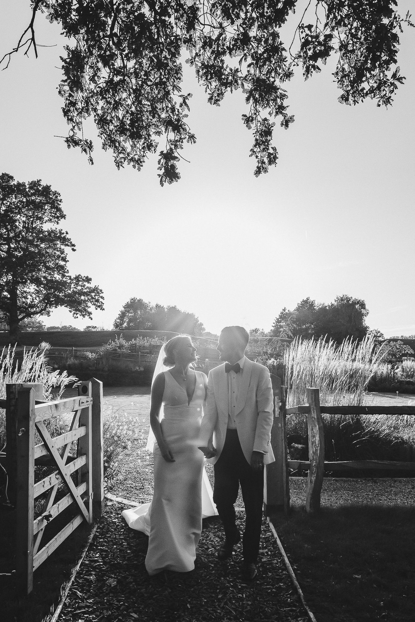 Black and white photo of wedding attire hanging on a clothesline outdoors with sunlight filtering through trees.