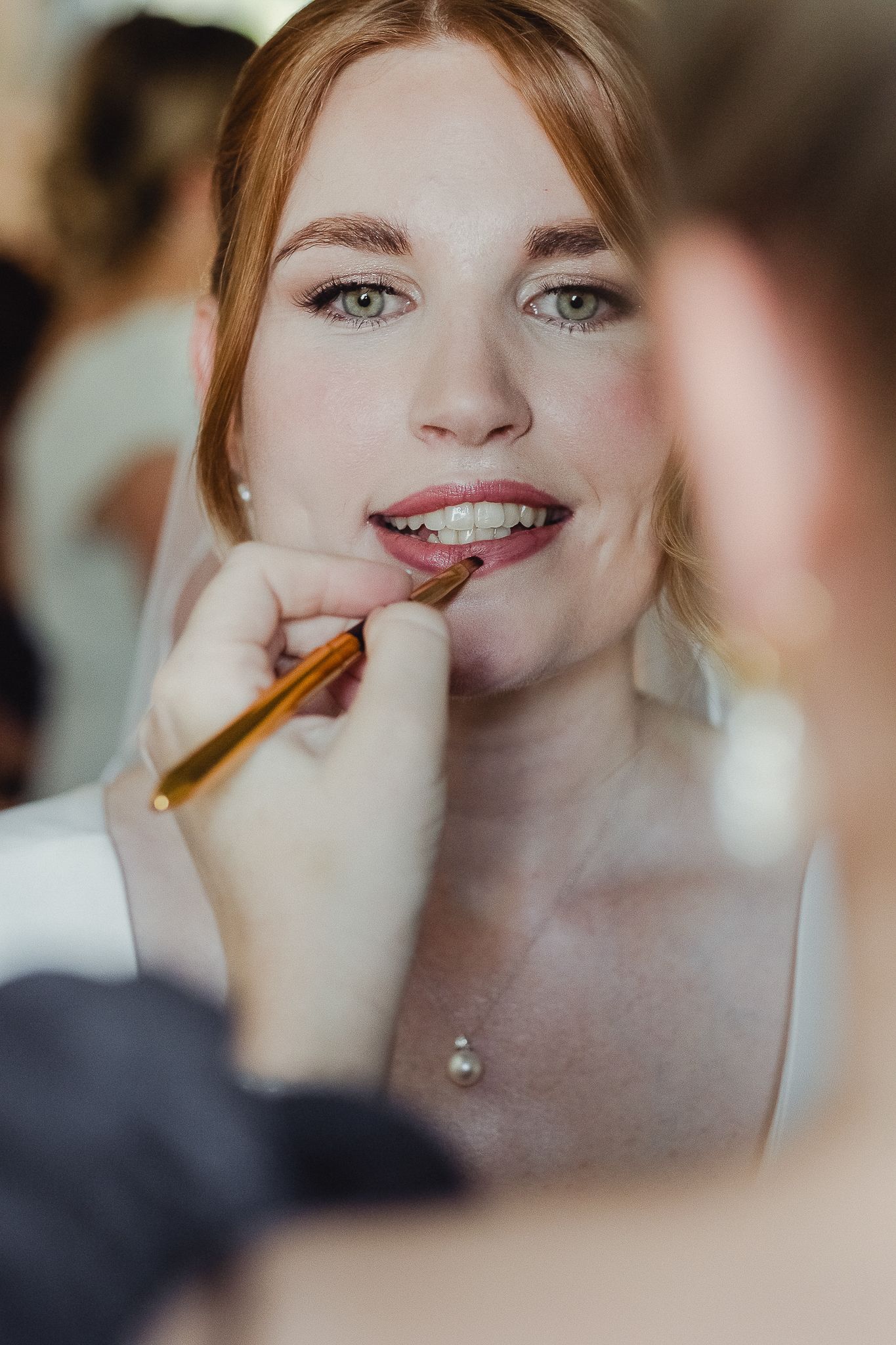 A makeup artist applies lipstick to a smiling person wearing braces in a series of closeup shots.