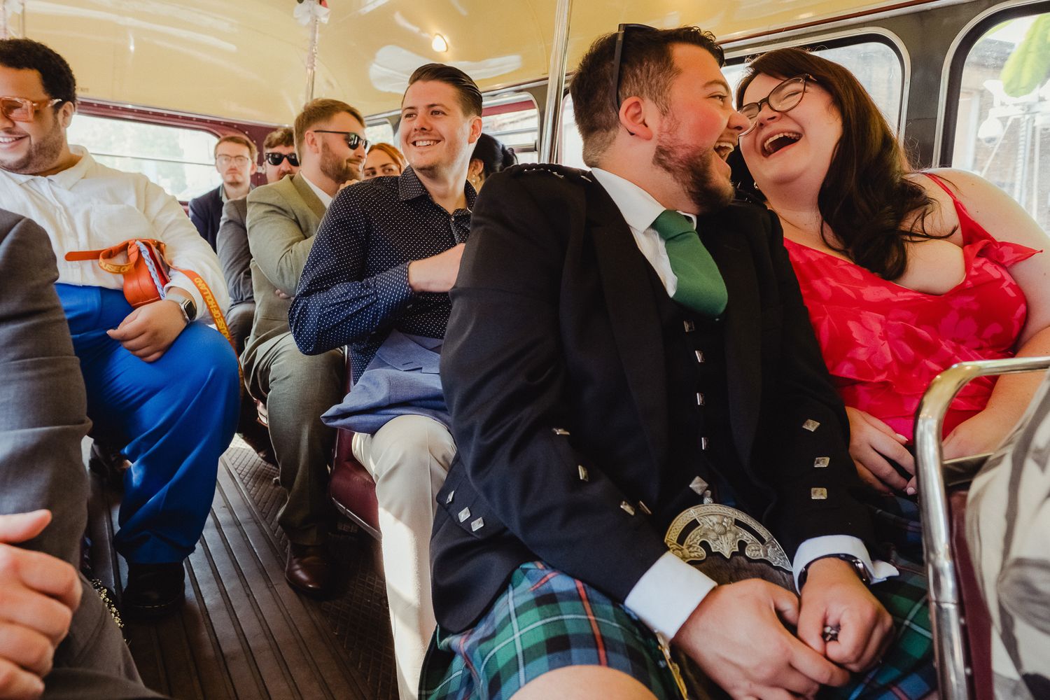 Lively group of wedding guests share joyful laughter while riding together on a vintage bus.