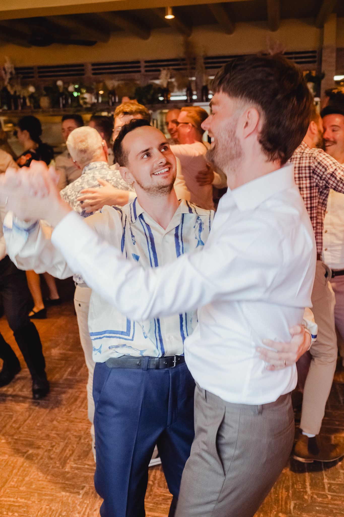 Two dancers perform traditional dance moves in formal attire at a social gathering.