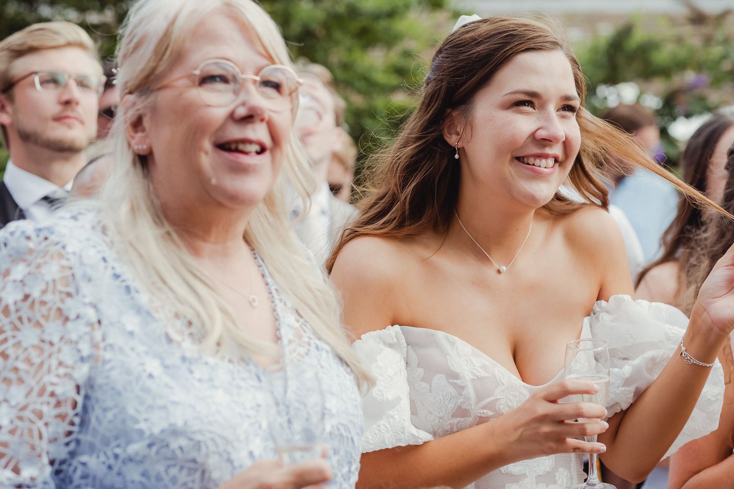 Wedding guests react with joy and laughter during an outdoor celebration.