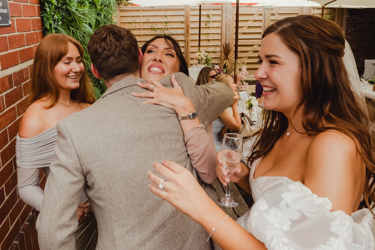 A candid moment of laughter and joy shared between a group at a wedding celebration outdoors.