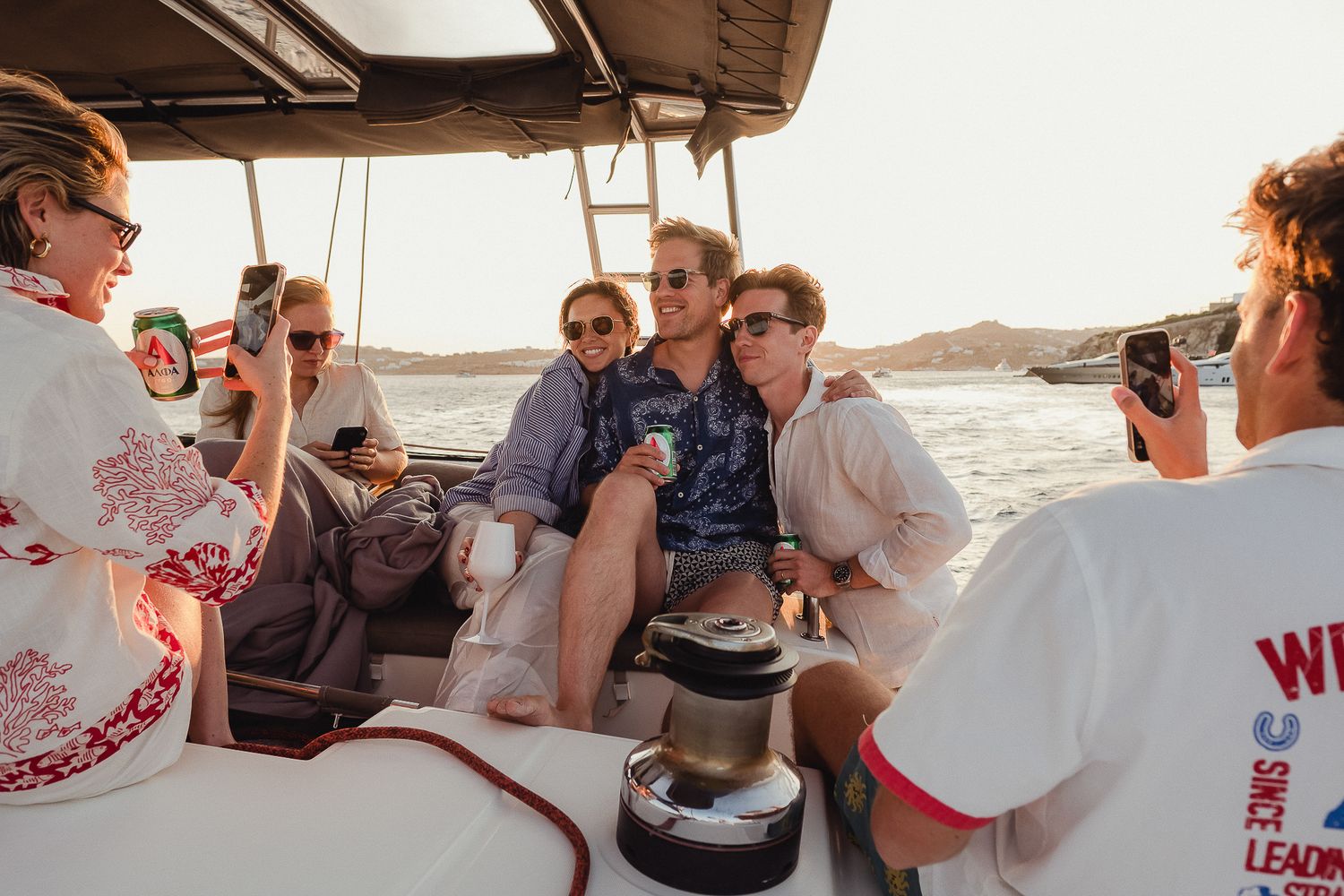 Group of people enjoying a boat ride at sunset with cameras and casual attire.