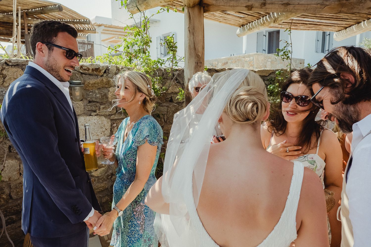 Candid moments between wedding guests interacting and mingling at an outdoor reception venue in warm sunlight.