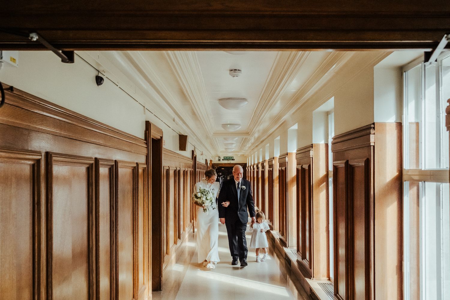 A long beige and brown hotel corridor with modern wood paneling and soft lighting creates an elegant atmosphere.