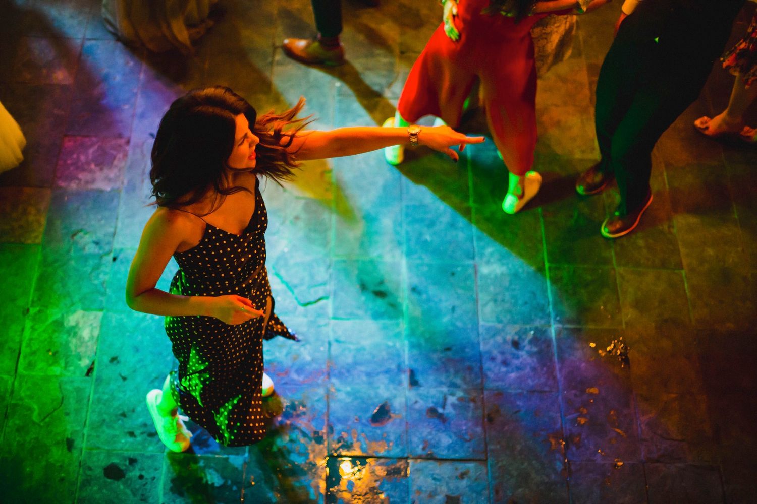 Dance floor illuminated with vibrant rainbow colored lights during wedding reception.