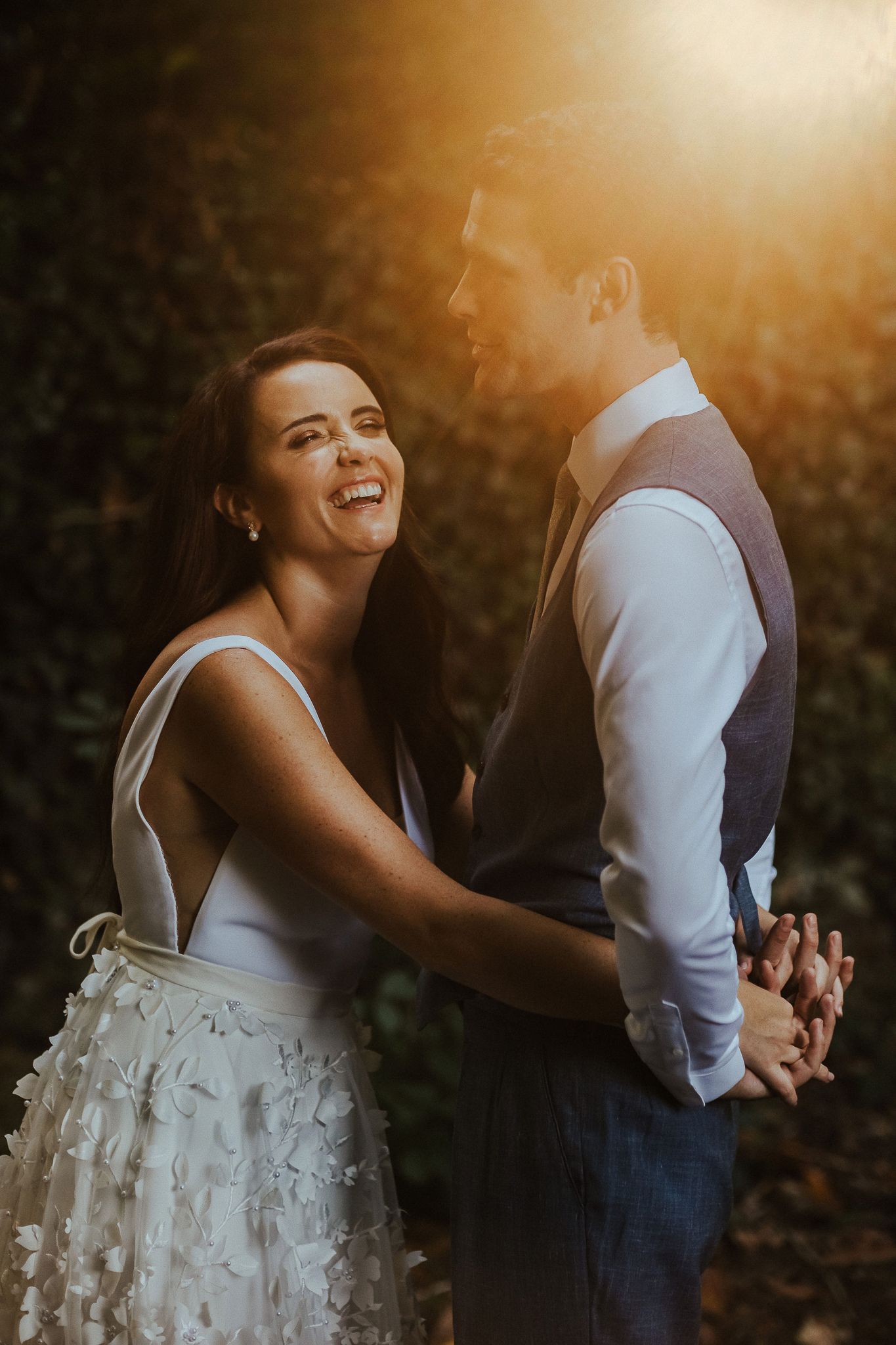 Bride and groom share intimate moment in golden sunset light.