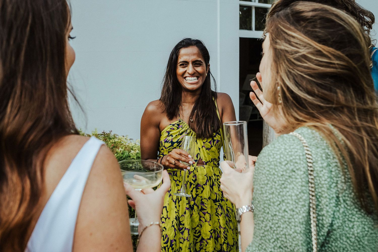 Wedding guests enjoying champagne and conversation at an outdoor garden party.