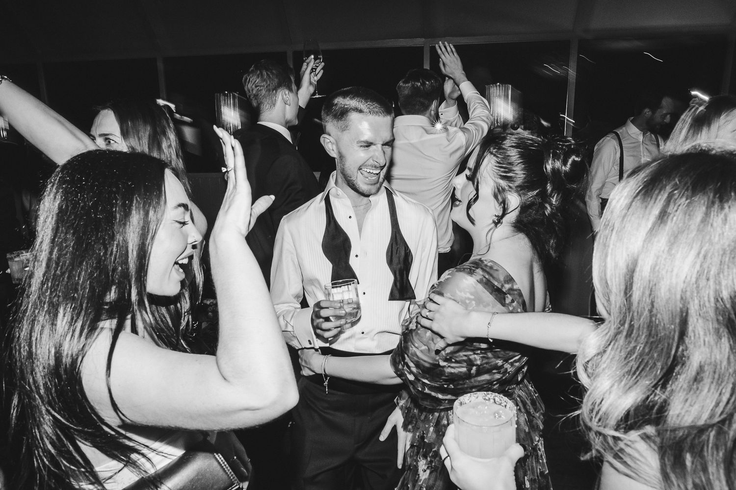 Black and white photo of people dancing and socializing at a crowded nightclub or party venue.
