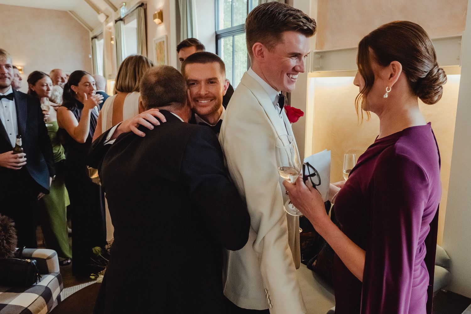 A group of people socializing and mingling at an indoor event with drinks in hand.