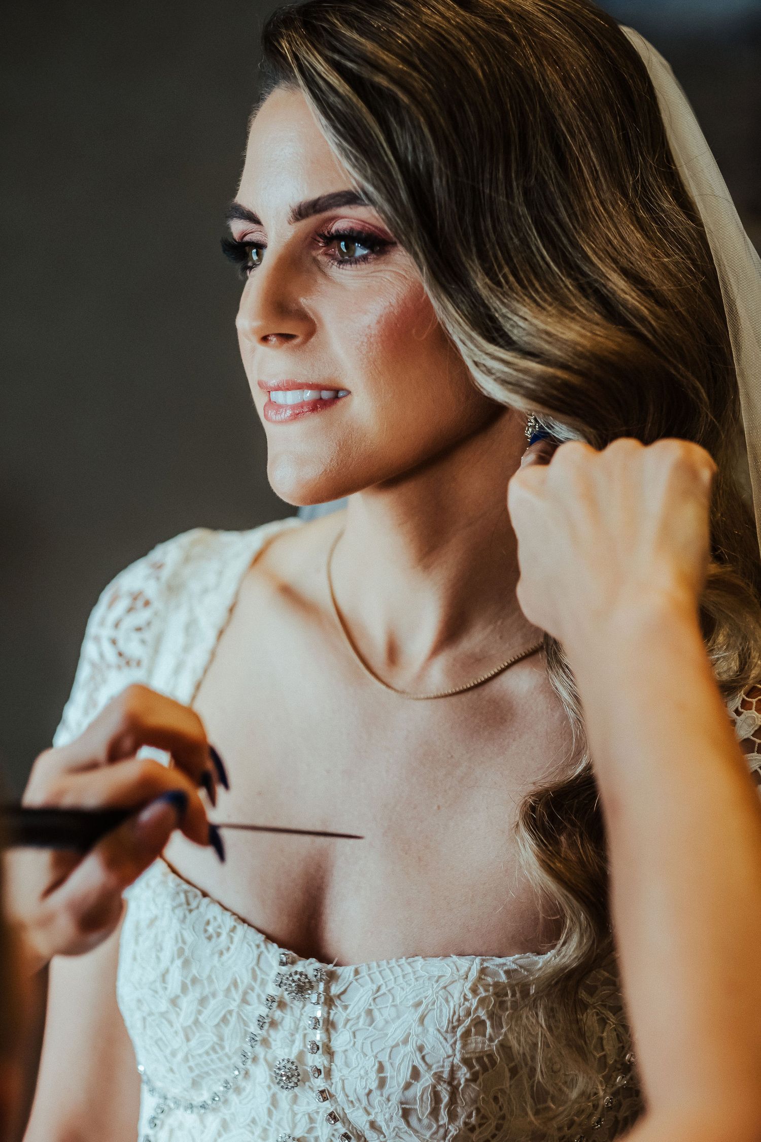 Close-up sequence of a bride getting ready, adjusting earrings while wearing a delicate lace wedding dress.