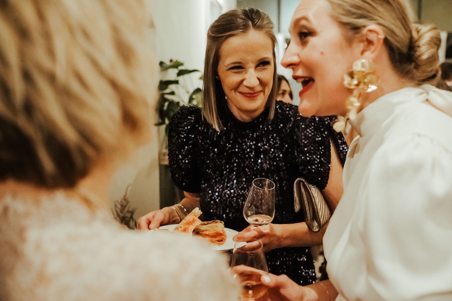 People sharing laughter and conversation while holding wine glasses during an elegant social gathering.