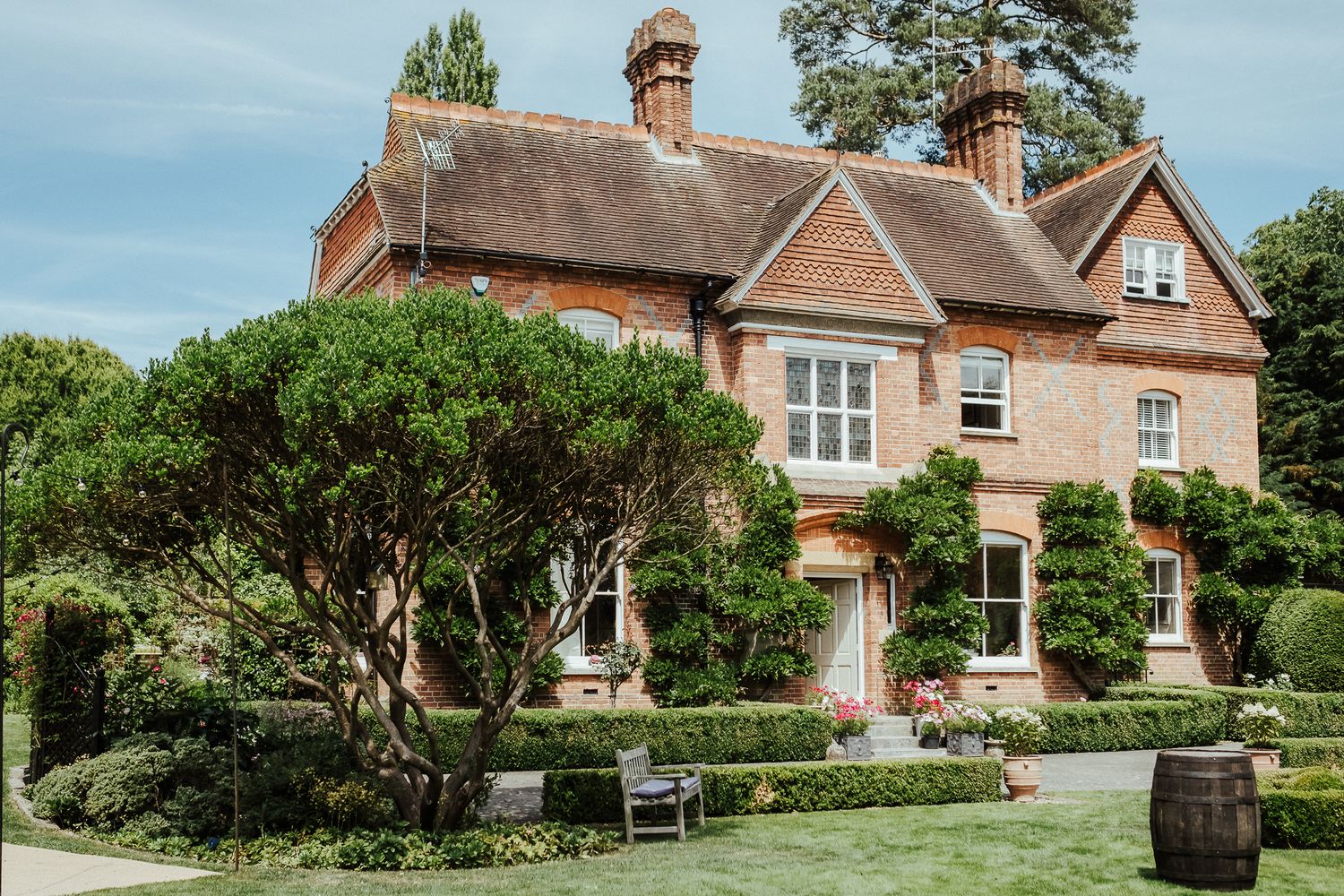 Traditional English country house with manicured gardens and red brick facade.