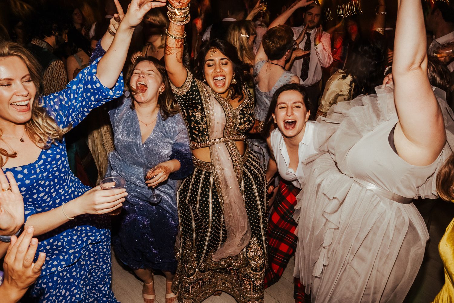 Energetic dance party with guests celebrating in a dimly lit venue.