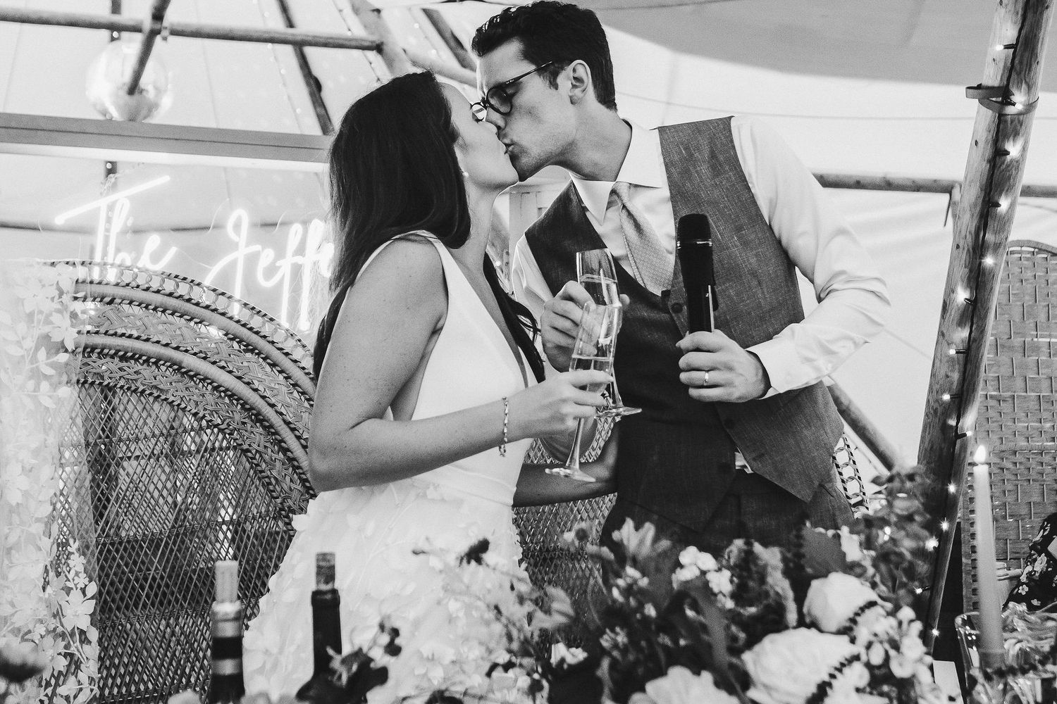 Black and white photo of couple sharing intimate moment with drinks at wedding reception.