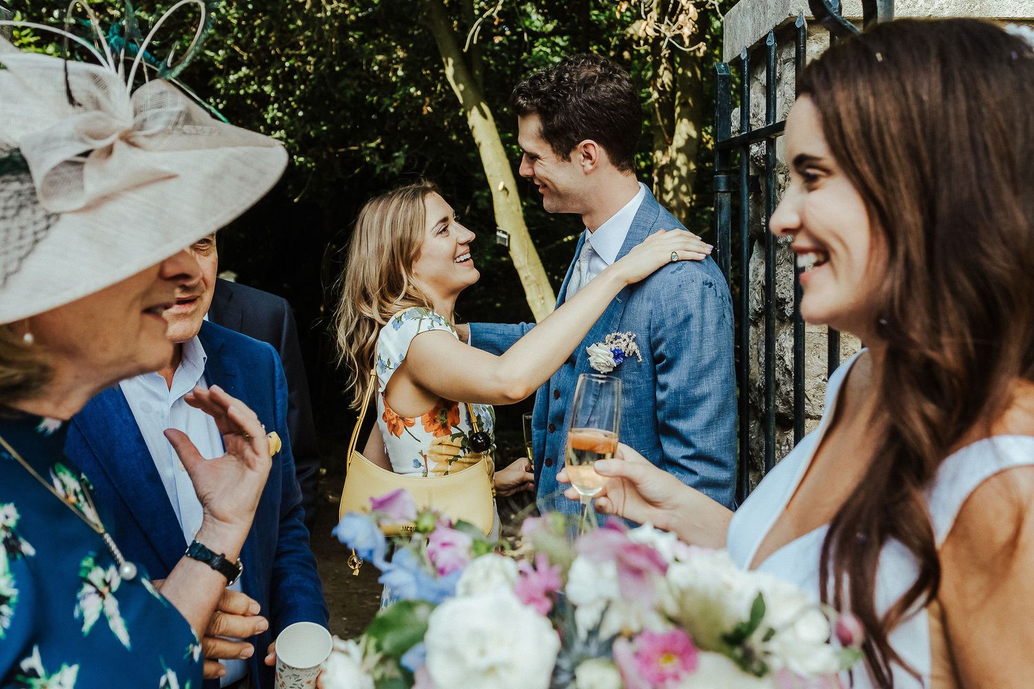 Guests mingling during an outdoor wedding celebration with floral arrangements.