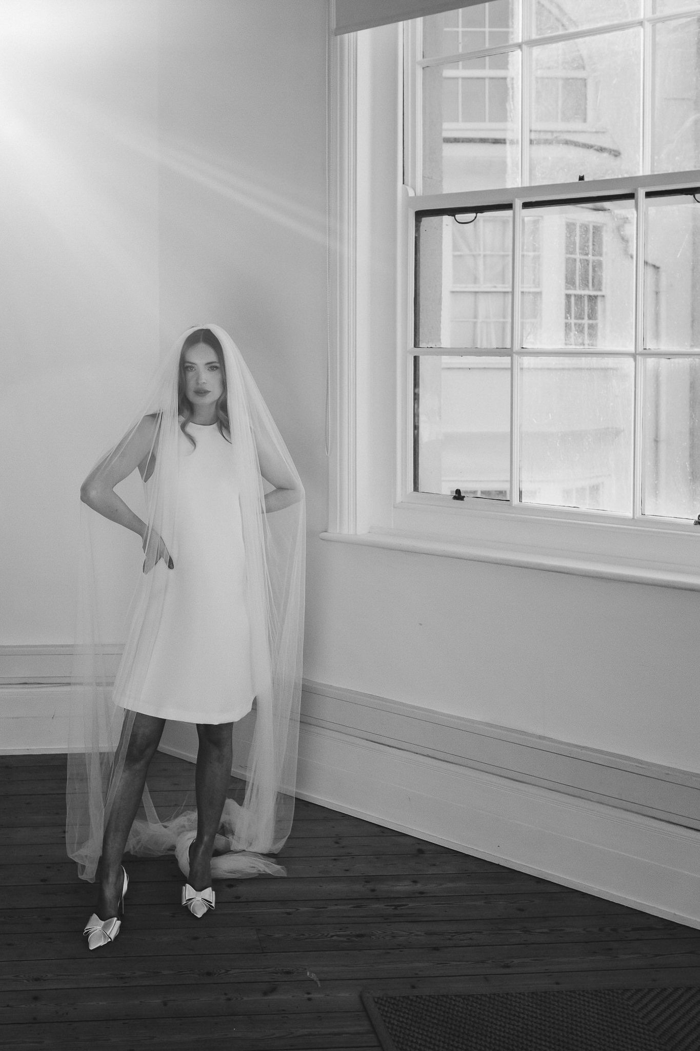 A series of black and white photographs showing a person in white clothing moving dynamically against a minimalist interior space.