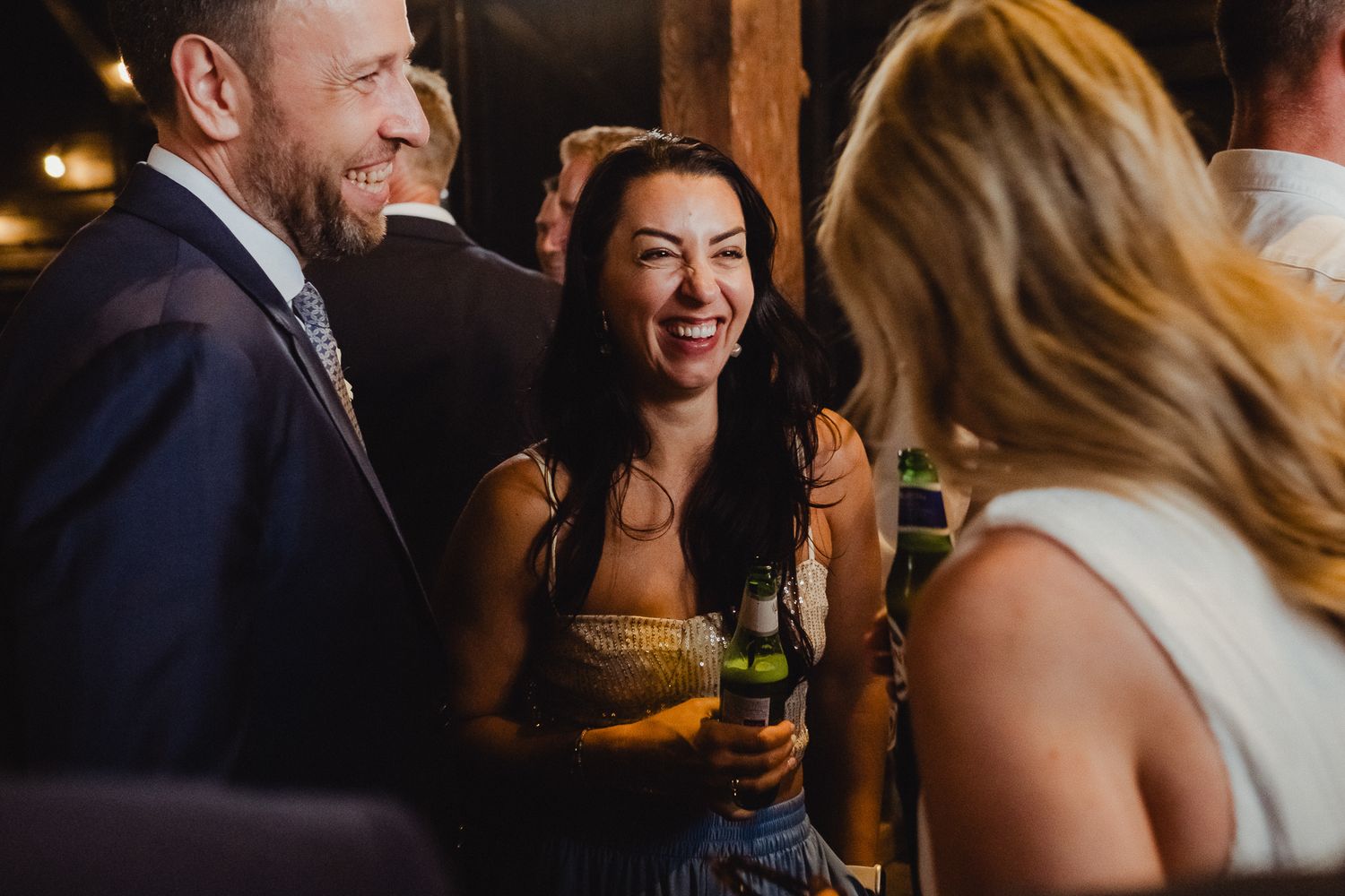 Guests share laughter and conversation during an evening social gathering at a warmly lit venue.