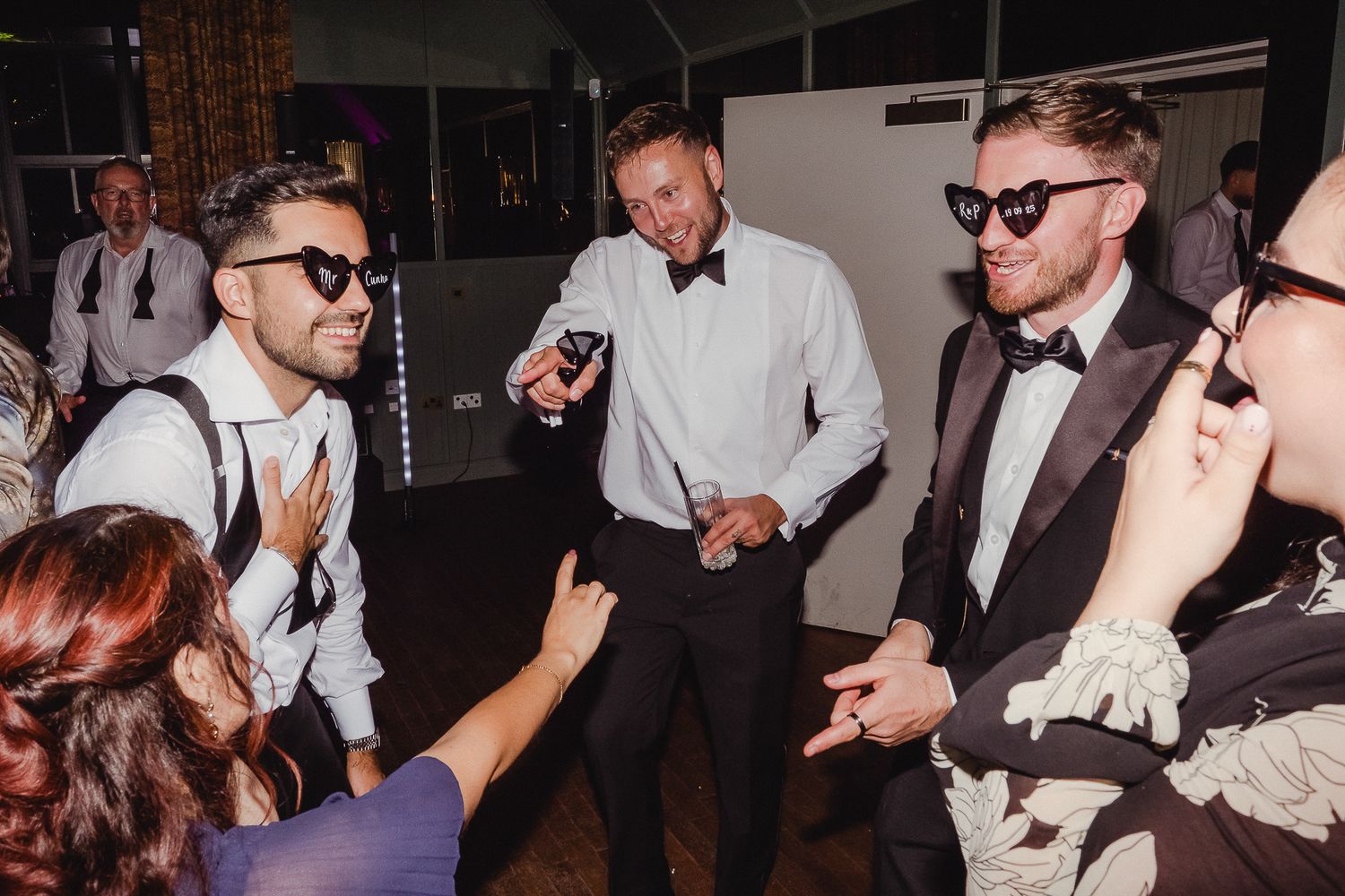 People dancing and celebrating at a lively wedding reception party with guests in formal attire.
