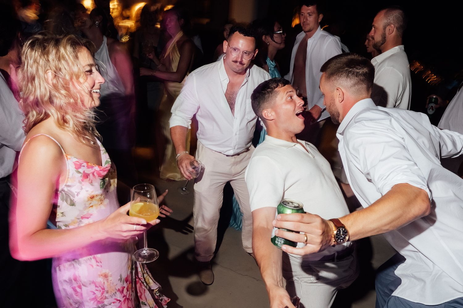 Guests laughing and dancing together at a lively wedding reception party celebration.
