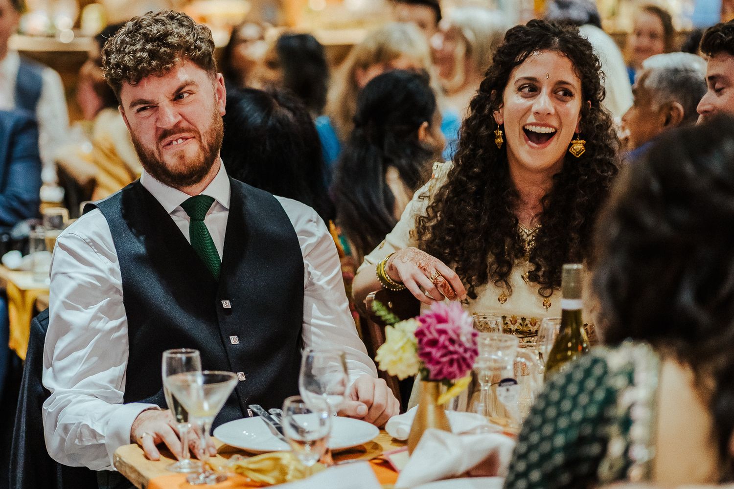 Wedding couple sharing a candid moment of laughter during their reception dinner.