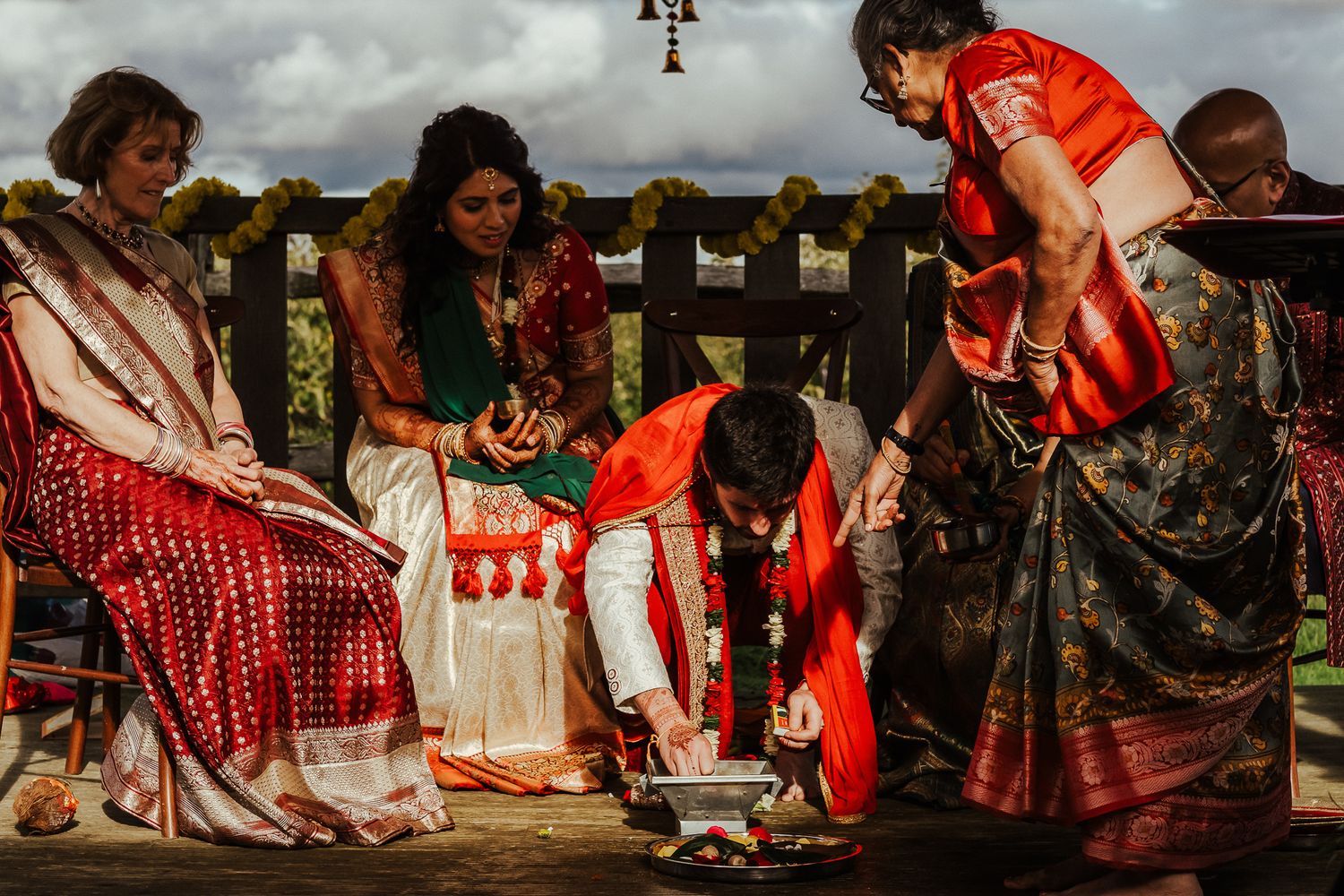 Traditional wedding ceremony participants perform rituals on an outdoor wooden platform.