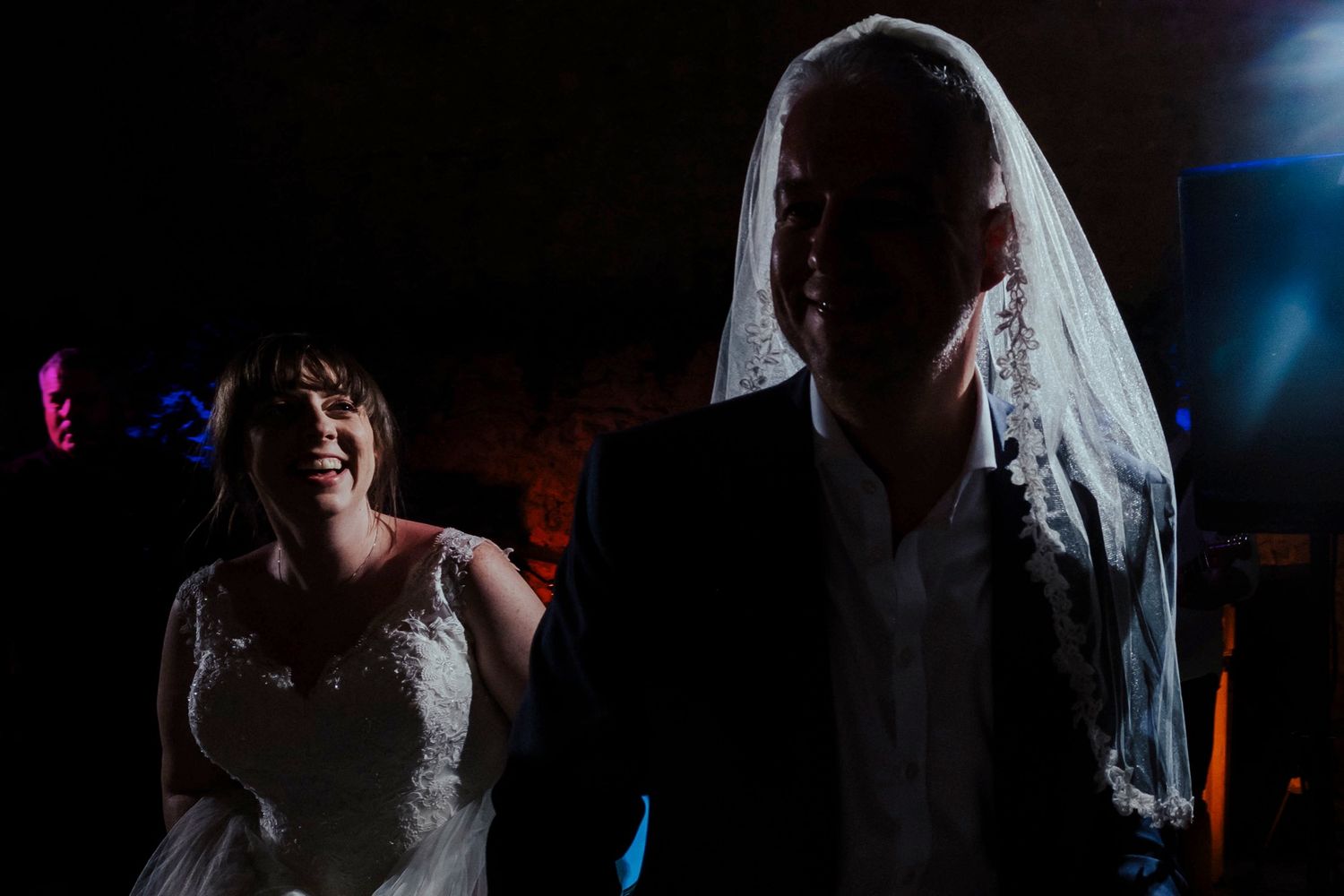 Dramatic silhouette of a dancing couple lit by colorful party lights.