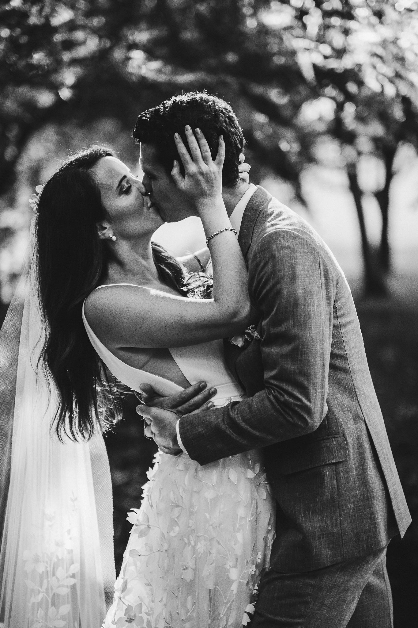 Black and white portrait of an intimate wedding embrace outdoors.