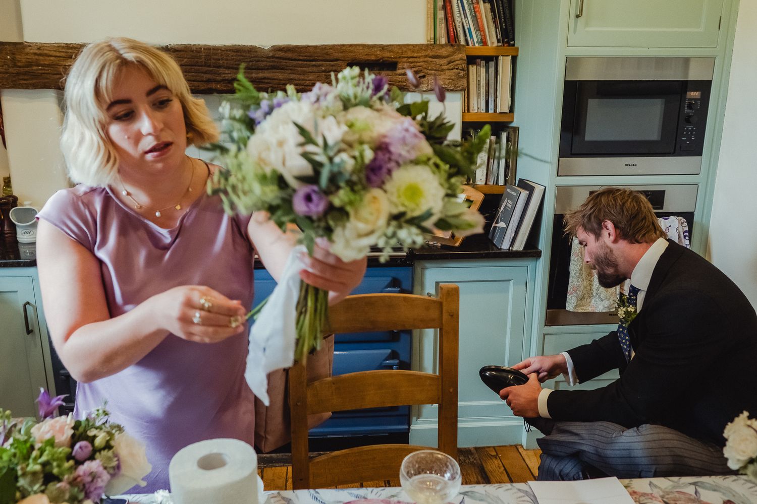 People enjoying a dinner gathering at home with wine and flowers on the table.