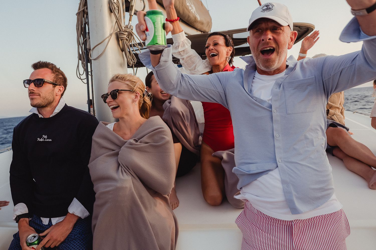 People dancing and celebrating on a boat with drinks and festive energy while enjoying a private party at sea.