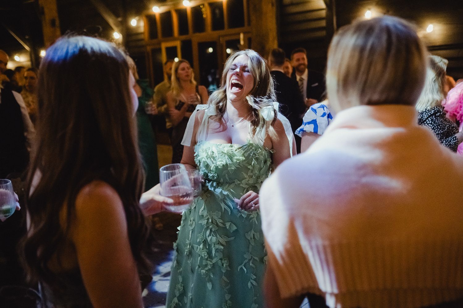 A group of people dancing and celebrating at a dimly lit wedding reception.