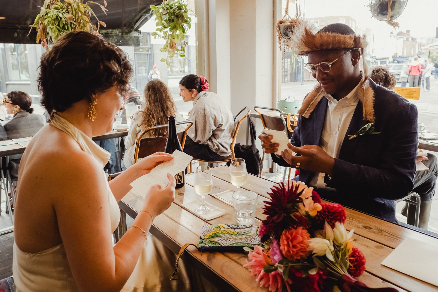 Guests enjoy a wine tasting experience at a rustic wooden table in a bright, modern restaurant setting.