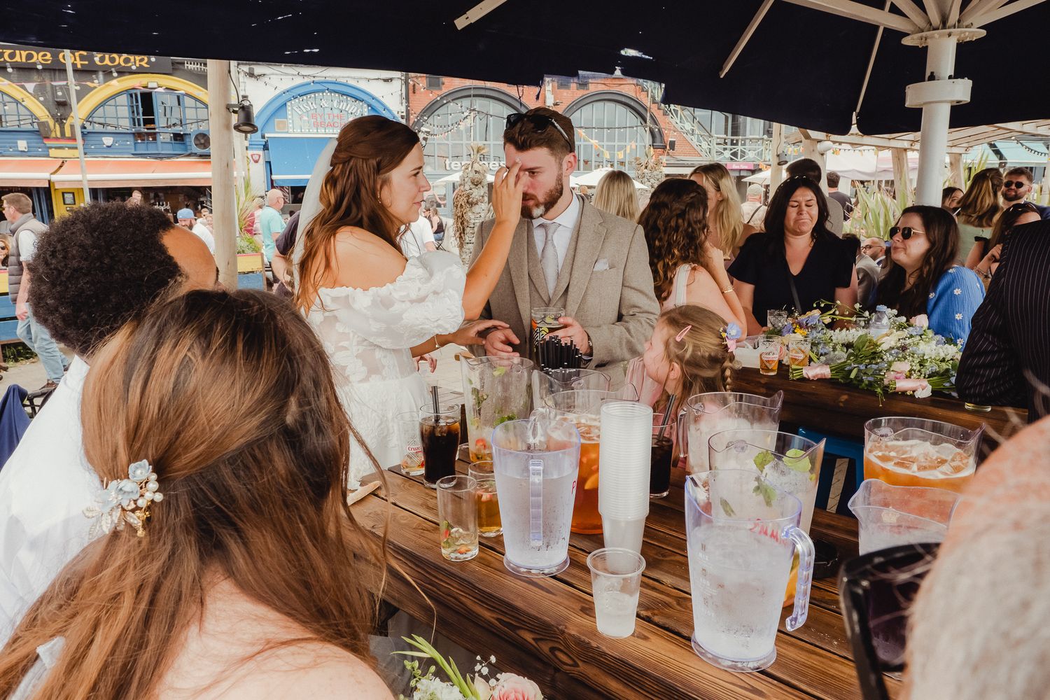 Wedding guests enjoy a lively reception celebration under a white tent with rustic decor and natural lighting.