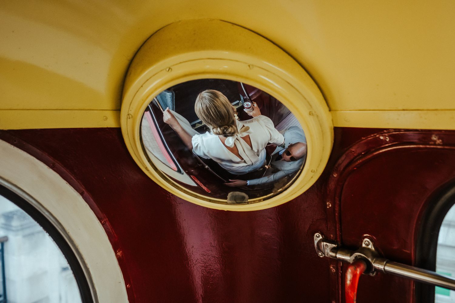 A rear view car mirror reflects a reclining car seat with a passenger inside against a burgundy and yellow interior.