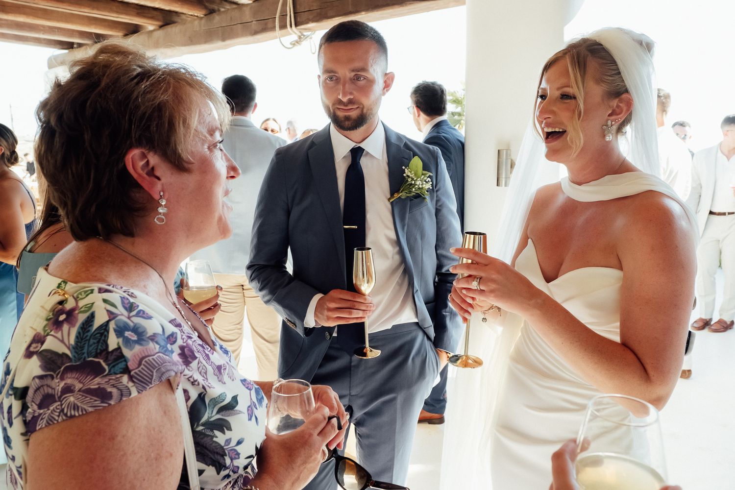 Bride in white gown toasting champagne with guests at wedding reception indoors.