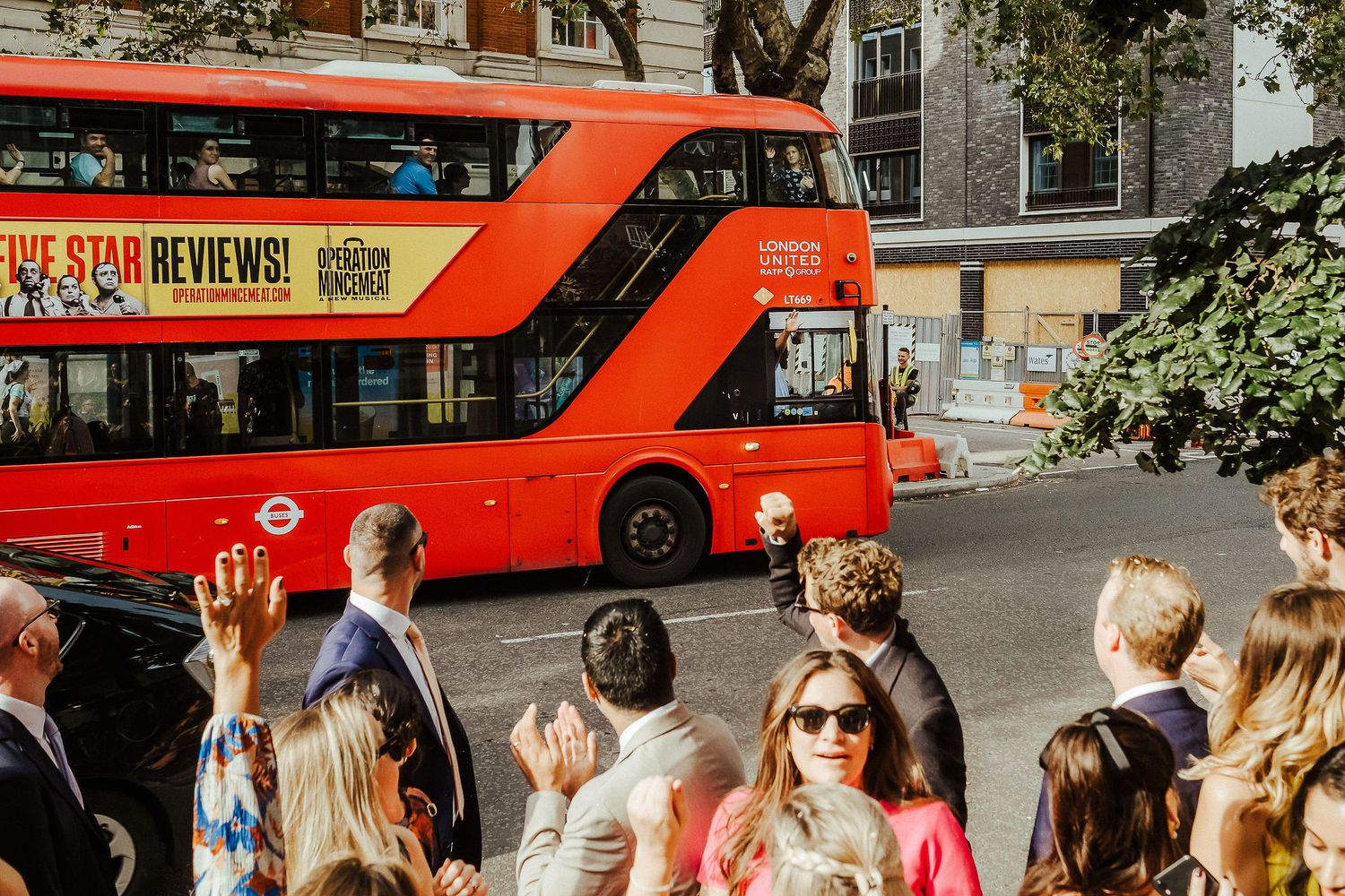 A busy London street scene with red double-decker buses and pedestrians walking on the sidewalk.