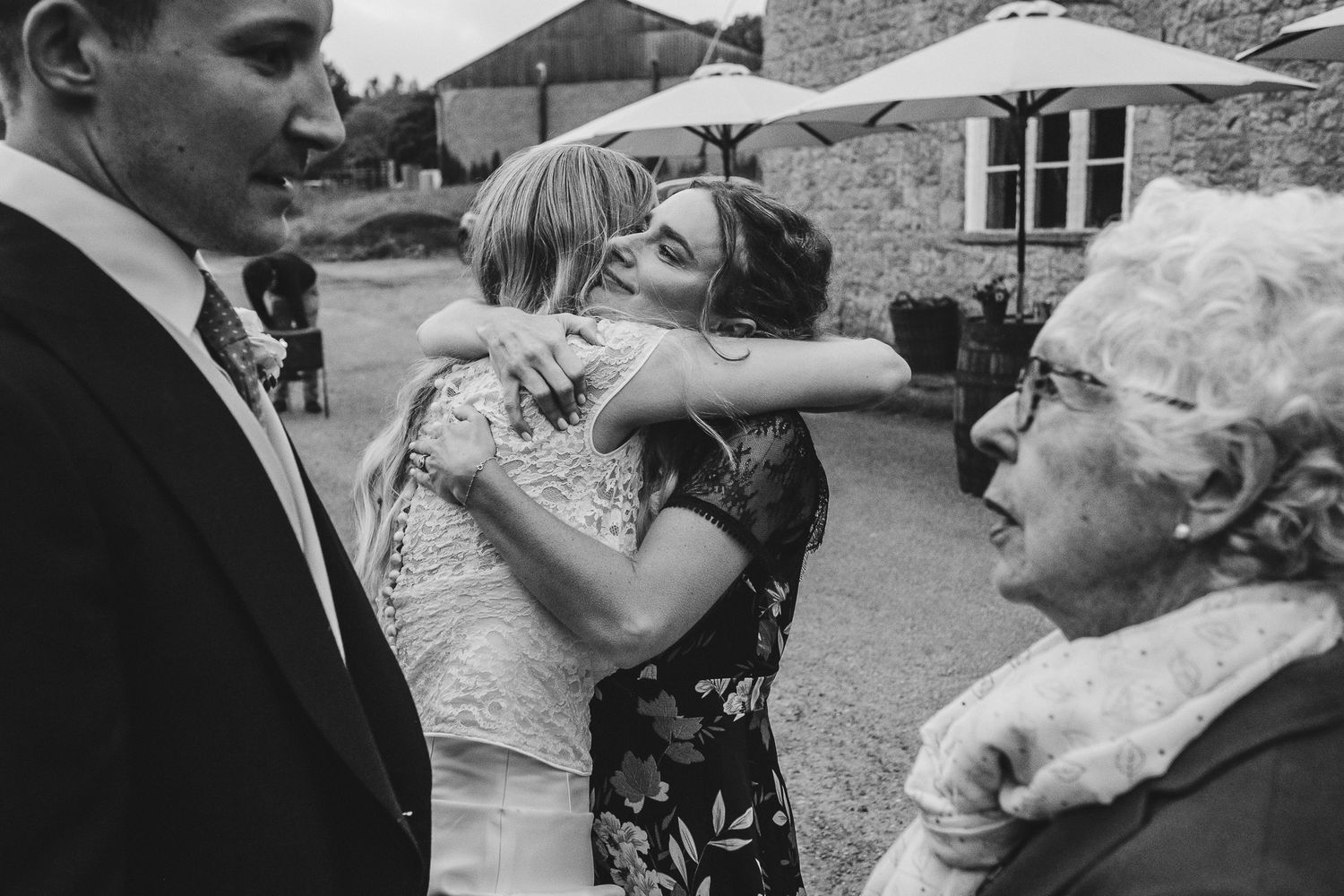 A candid moment at an outdoor wedding celebration showing guests interacting near a brick building.