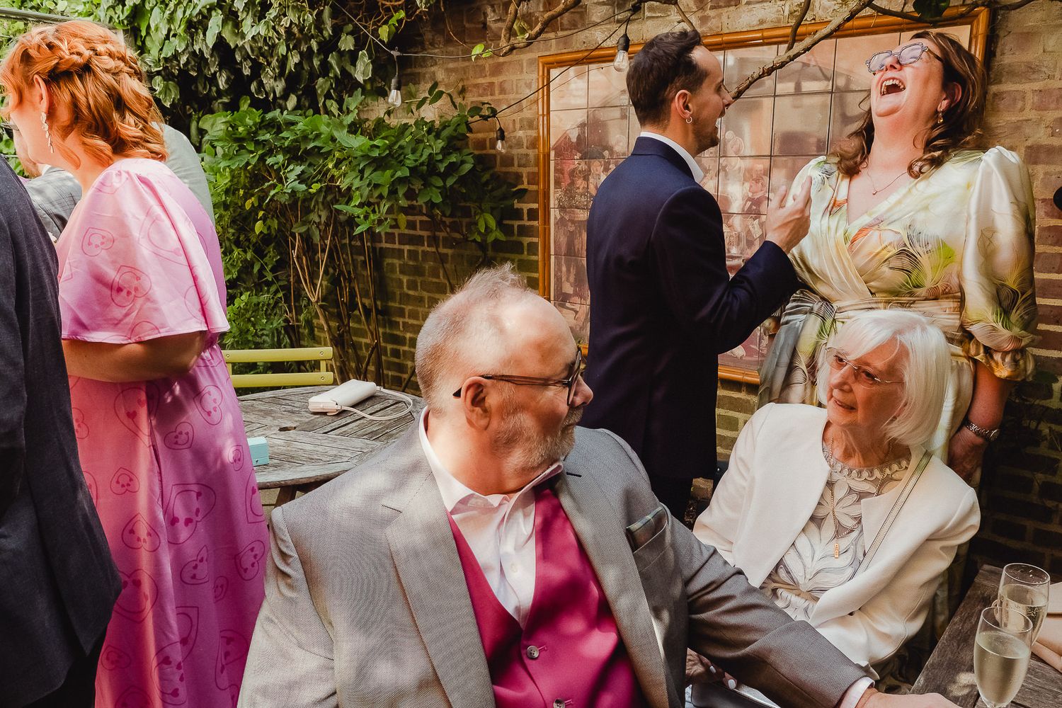 Wedding guests dance and celebrate together during a joyful reception in a rustic brick-walled venue.