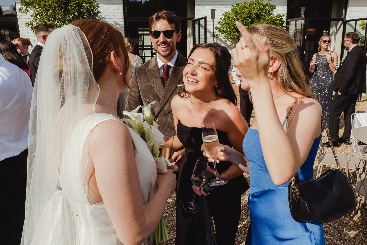 Wedding guests enjoying drinks and conversation during an outdoor reception celebration.