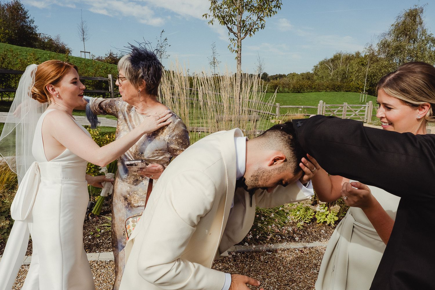 Candid moment at an outdoor wedding celebration with guests playfully interacting in a garden setting.
