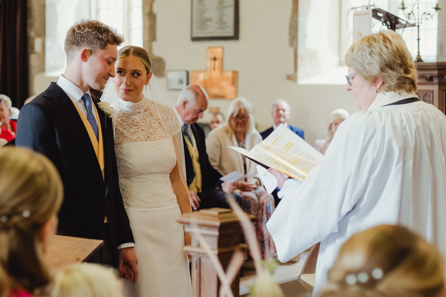 Wedding guests mingle and chat during an elegant indoor reception with light streaming through windows.