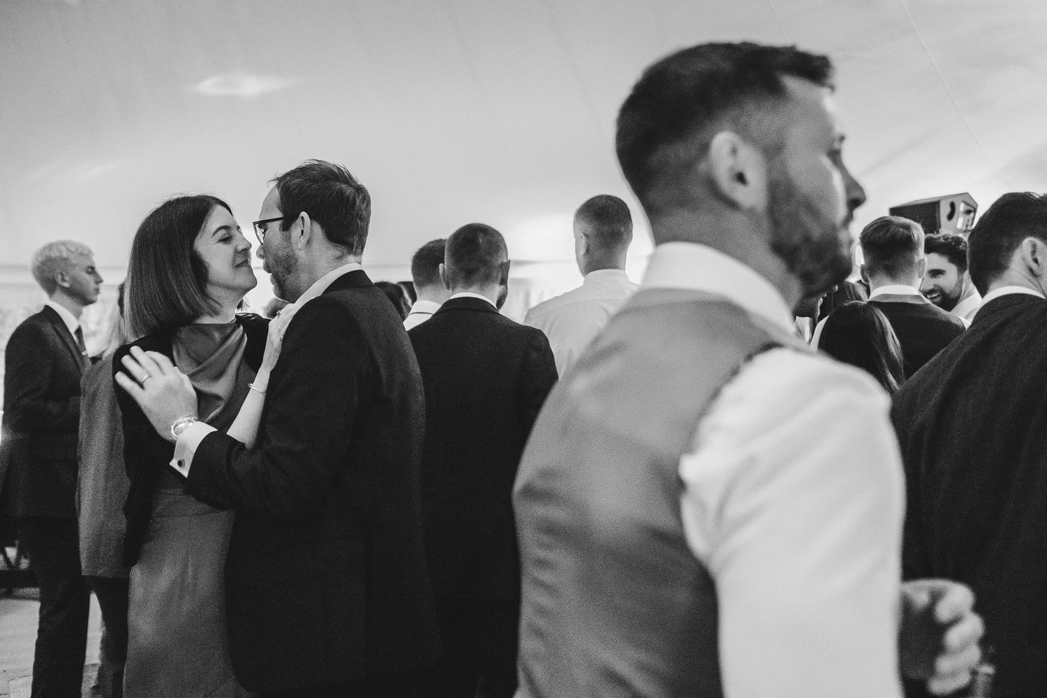 A black and white panoramic photo shows couples dancing together at an elegant wedding reception.
