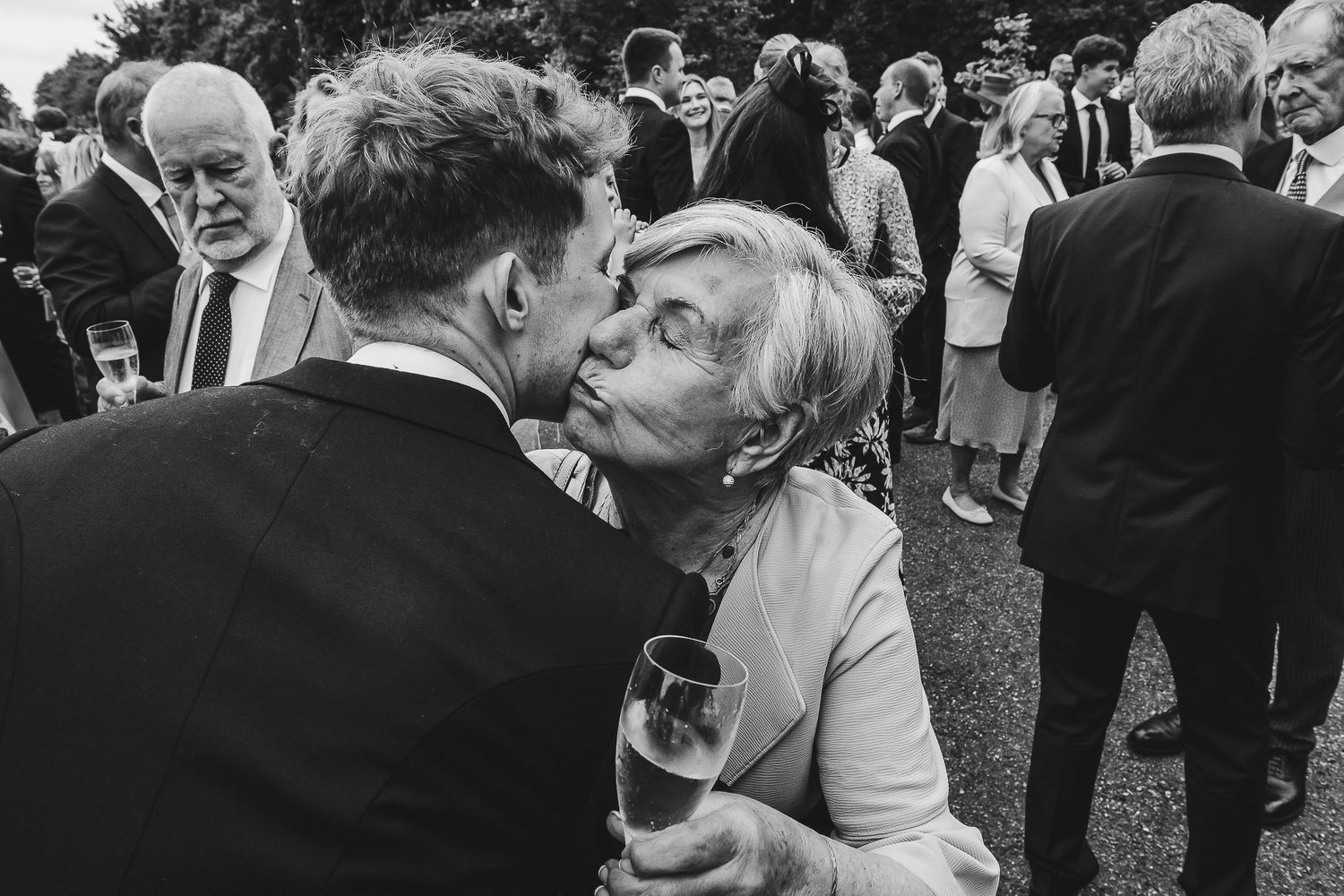 A black and white wedding photograph showing a couple dancing together at an outdoor reception celebration.