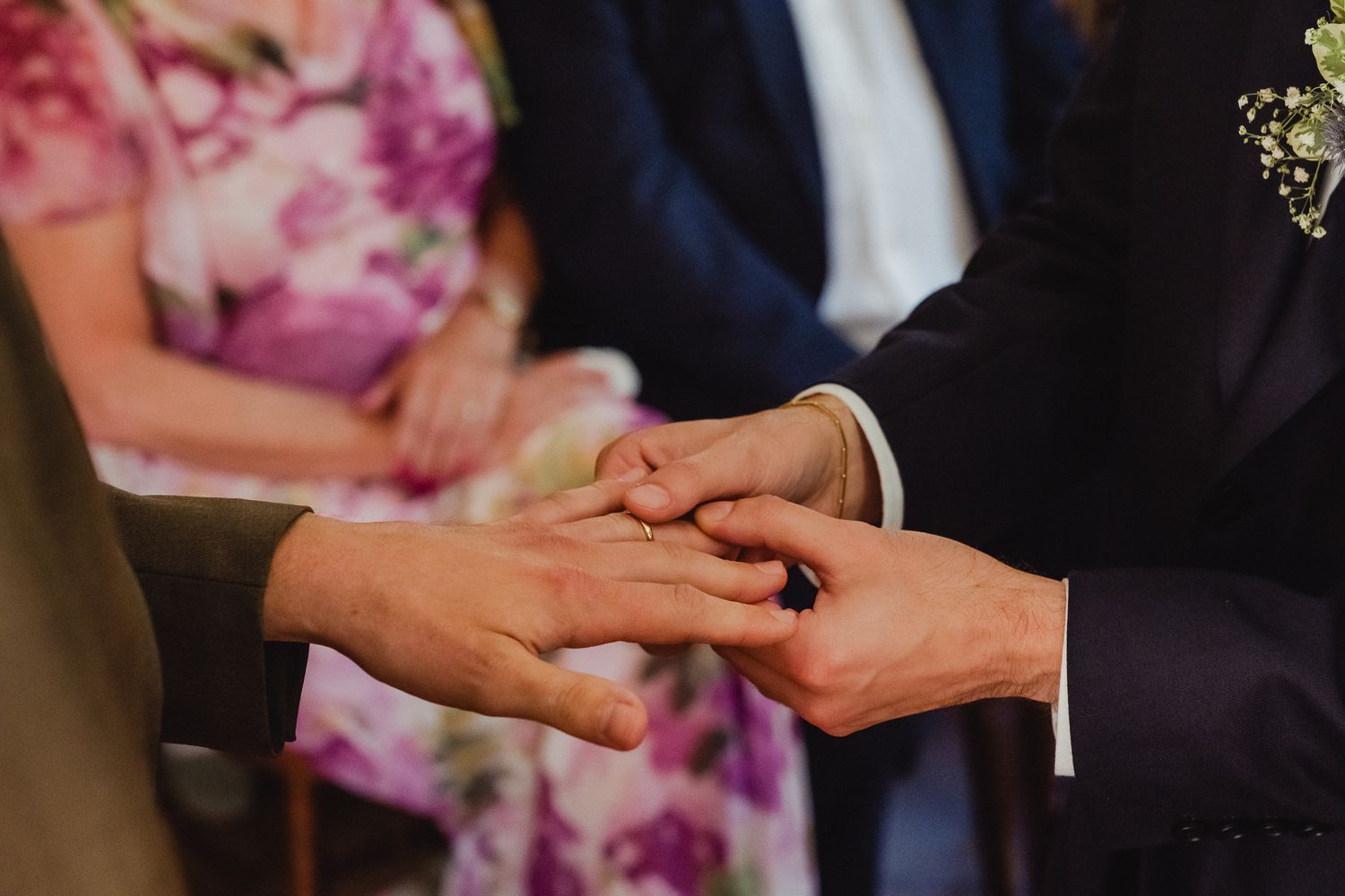 A couple holds hands during a romantic wedding ceremony moment in formal attire.