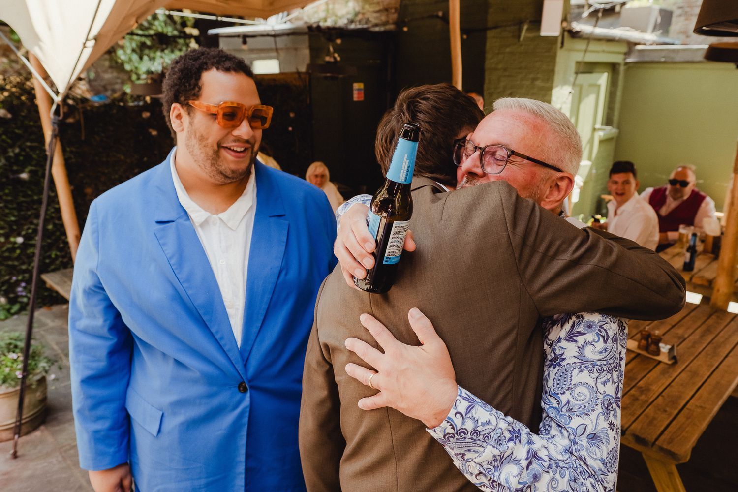 A group of people embrace and celebrate together in a casual indoor setting.